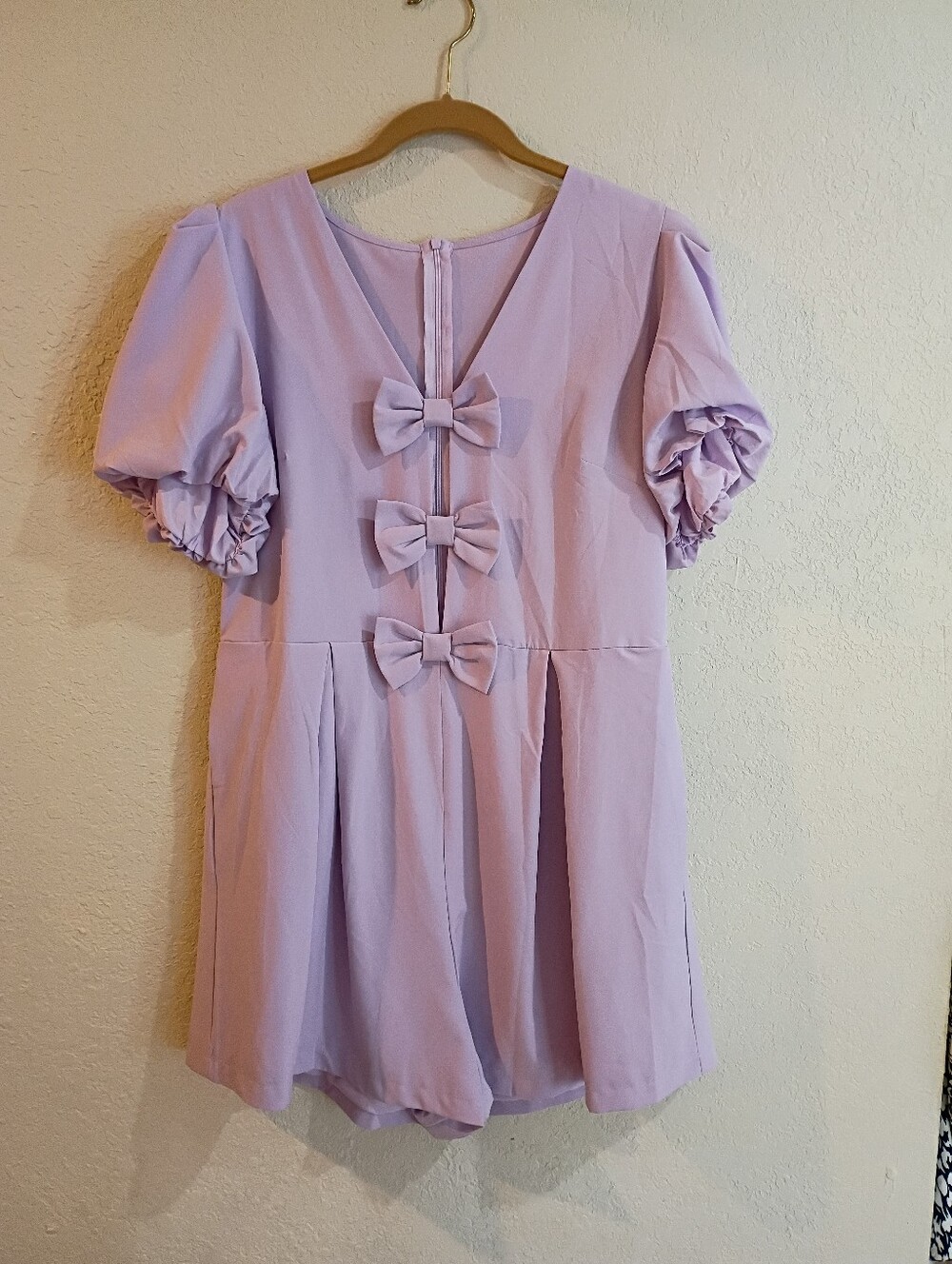 Lavender romper with bow accents, pockets and zipper closure. Size XL.